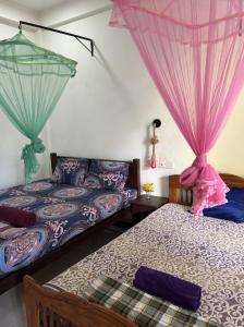 two beds in a room with pink drapes at Lobster Inn in Trincomalee