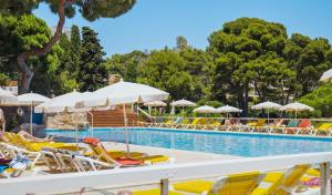 a swimming pool with lounge chairs and umbrellas at htop Caleta Palace - Bliss in Platja d'Aro