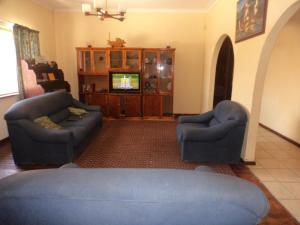 sala de estar con 2 sillas azules y TV en Namibia Skipper Services en Walvis Bay