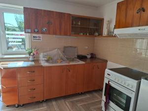 a kitchen with wooden cabinets and a sink and a stove at Gardenhouse in Mëmëlisht