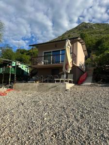 a house with a patio with a umbrella and chairs at Holiday home Ramovic in Virpazar