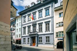 a large white building with a flag on it at Tailormade Hotel RÜDEN Schaffhausen in Schaffhausen