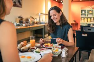 a woman sitting at a table eating food at Tailormade Hotel RÜDEN Schaffhausen in Schaffhausen