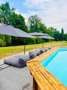 a swimming pool with umbrellas and lounge chairs next to a swimming pool at Gutshaus Groß Helle in Mölln