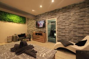 a bedroom with a stone wall with a bed and a tv at Apartmán Elarys in Nezdenice