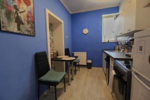 a kitchen with blue walls and tables and chairs at Apartmán Elarys in Nezdenice