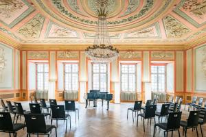 a large room with a chandelier and tables and chairs at Tailormade Hotel RÜDEN Schaffhausen in Schaffhausen