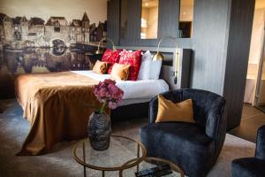a bedroom with a bed with a vase of flowers and a chair at Van der Valk Hotel Amersfoort-A1 in Amersfoort +56 photos