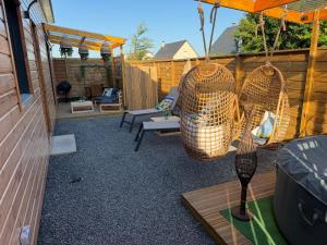 a patio with a swing and chairs and a fence at gîte romantique in Etalondes-la-Pipe