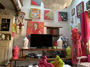 a room with a desk with a television and paintings on the wall at Maison de charme du 18 e s de centre ville in Sablé-sur-Sarthe
