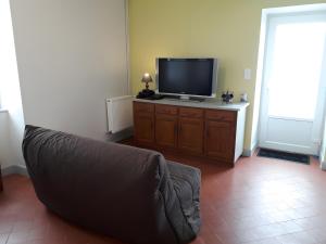 a living room with a couch and a flat screen tv at Gîte la Roche du Gravillot in Château-Chinon