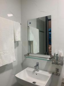 a white bathroom with a sink and a mirror at T&T Luxury Hotel Đồi Ngô in Bắc Ninh