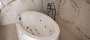 eine weiße Badewanne in einem Badezimmer mit Marmorwänden in der Unterkunft hôtel Benkachour in Oujda + 17 Fotos