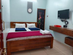 a bedroom with a wooden bed with a tv on the wall at Malar Residency in Tirunallār