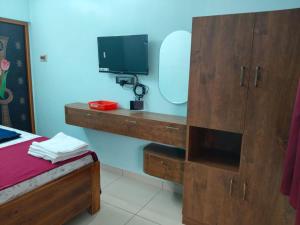 a room with a tv and a desk with a mirror at Malar Residency in Tirunallār +16 photos