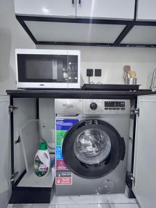 a microwave and a washing machine in a kitchen at Japandi vibe new apartment in Riyadh