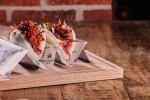 two tacos on a wooden plate on a wooden table at The Ripon Inn - The Inn Collection Group in Ripon