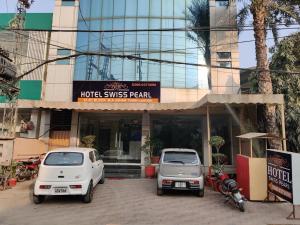 two cars parked in front of a building at Swiss Pearl Hotel Lahore in Lahore