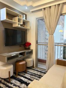 a living room with a tv and a large window at Cozy Place Curitiba in Curitiba
