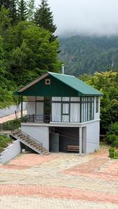 a small house with a green roof and a porch at Panorama Cottages Tbeti in Shuakhevi
