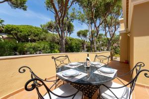 a table and chairs on a balcony with trees at Villa Praia Verde - Beach & Nature in Praia Verde
