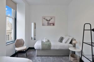 a white bedroom with a bed and a chair at Contractor-Friendly - Hawick - Free Parking - 2BR in Hawick