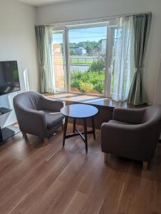 a living room with two chairs and a table and a window at 杉 Cedar House in Biei