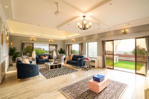 a living room with couches and chairs and windows at EKOSTAY Luxe - Noah Villa with Peddle Court & Sunset View in Lonavala