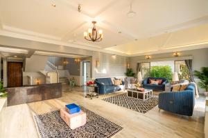 a living room with blue couches and a rug at EKOSTAY Luxe - Noah Villa with Peddle Court & Sunset View in Lonavala