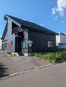 a black building on the side of a street at 杉 Cedar House in Biei