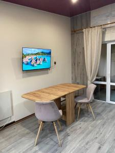 a dining room with a wooden table and a tv on a wall at Forest Edge house in Kolonshchina