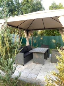 a patio with a table and a couch under an umbrella at Forest Edge house in Kolonshchina