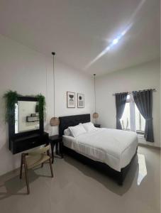 a white bedroom with a large bed and a mirror at Kama villa in Uluwatu