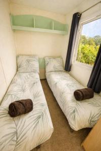 two beds in a small room with a window at The Lodge - 3BR, Woodland Forge, Garden Patio, Parking, Sleeps 6 in Over Whitacre