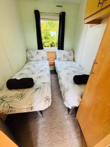 two beds in a small room with a window at The Lodge - 3BR, Woodland Forge, Garden Patio, Parking, Sleeps 6 in Over Whitacre