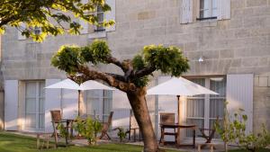 two tables and chairs with umbrellas in front of a building at COMO Cordeillan-Bages in Pauillac +17 photos