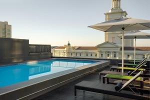 a swimming pool with umbrellas and benches next to a building at Protea Hotel by Marriott Cape Town North Wharf in Cape Town