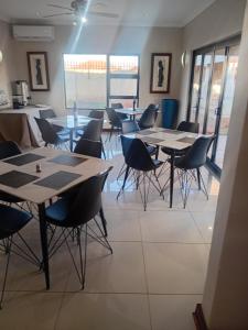 a group of tables and chairs in a room at The Grand Village in Mahikeng +1 photo