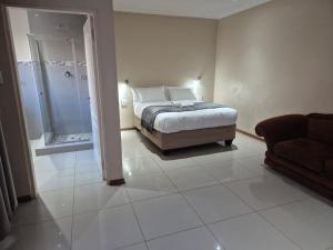 a bedroom with a bed and a shower and a couch at The Grand Village in Mahikeng