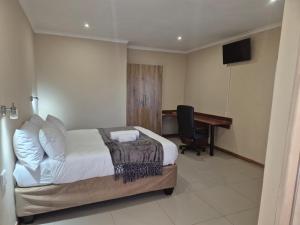 a bedroom with a bed and a desk with a computer at The Grand Village in Mahikeng