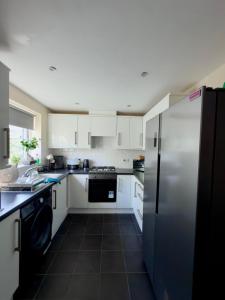 a kitchen with white cabinets and a stainless steel refrigerator at Blackrod Homestay in Blackrod