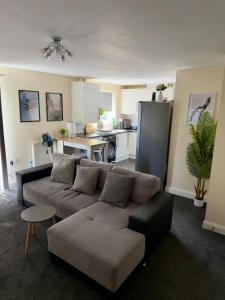 a living room with a couch and a kitchen at Blackrod Homestay in Blackrod