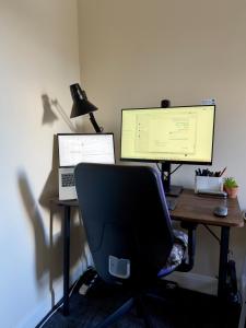 a desk with a computer and a monitor and a chair at Blackrod Homestay in Blackrod