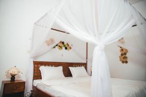 a bedroom with a canopy bed with white curtains at Belvédère Hôtel in Toliara +18 photos