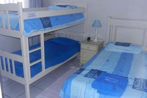 a bedroom with two bunk beds and a table with a lamp at Beach Cottage Abigail in Southbroom