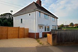 a white house with a wooden fence at Spacious 3 Bed House in Northampton - Sleeps 6 - Driveway Parking - Fast WiFi in Kingsthorpe