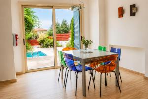 a dining room with a glass table and colorful chairs at Villa Serenity in Neo Chorio