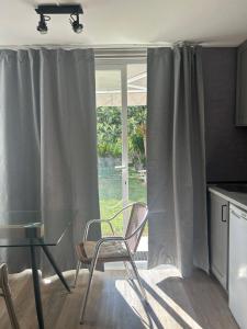 a kitchen with a glass table and chairs in front of a window at 5minutos do jardim até ao mar in Parede