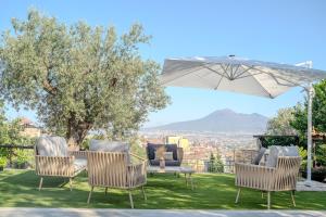 a group of chairs and a table and an umbrella at Grania Le Radici - Agriresort in Gragnano