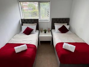 two beds in a room with red and white sheets at Spacious 3 Bed House in Northampton - Sleeps 6 - Driveway Parking - Fast WiFi in Kingsthorpe